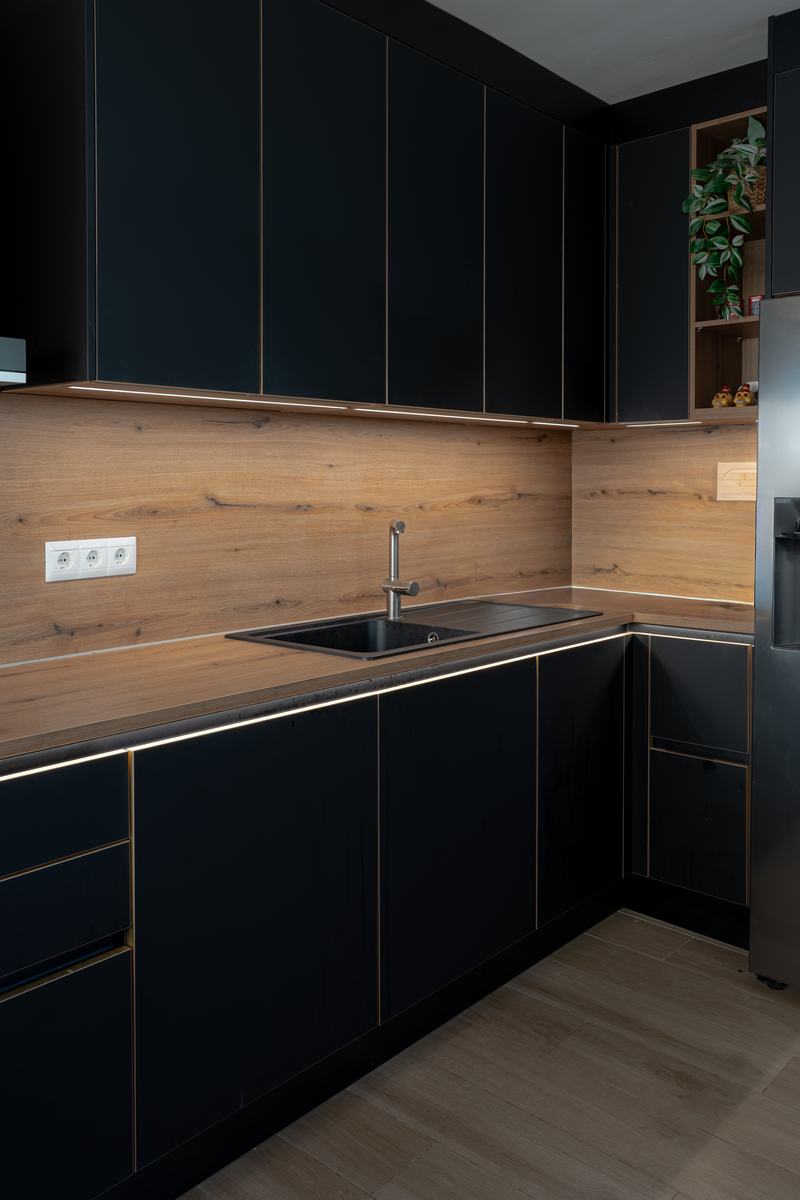 Cocina en negro con encimera de madera y luz bajo los muebles