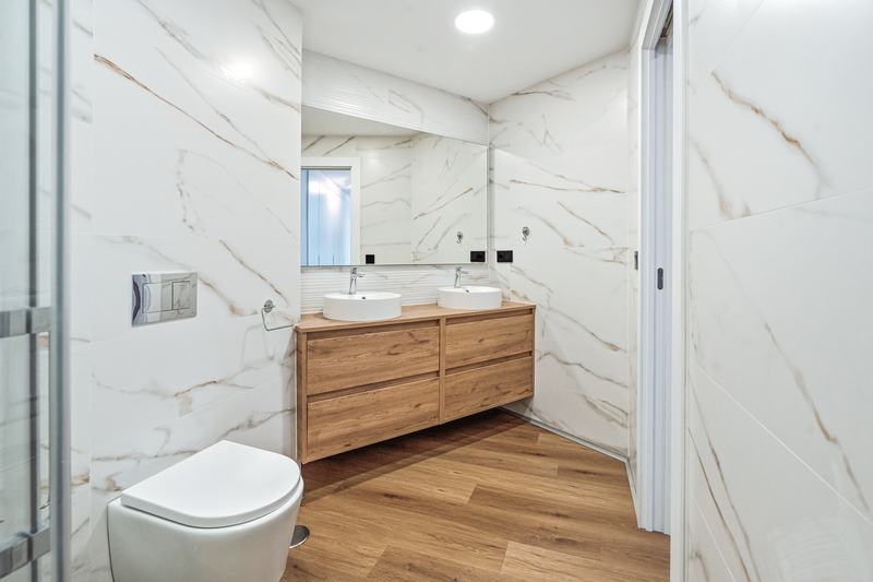 Baño en mármol con dos lavabos e inodoro suspendido