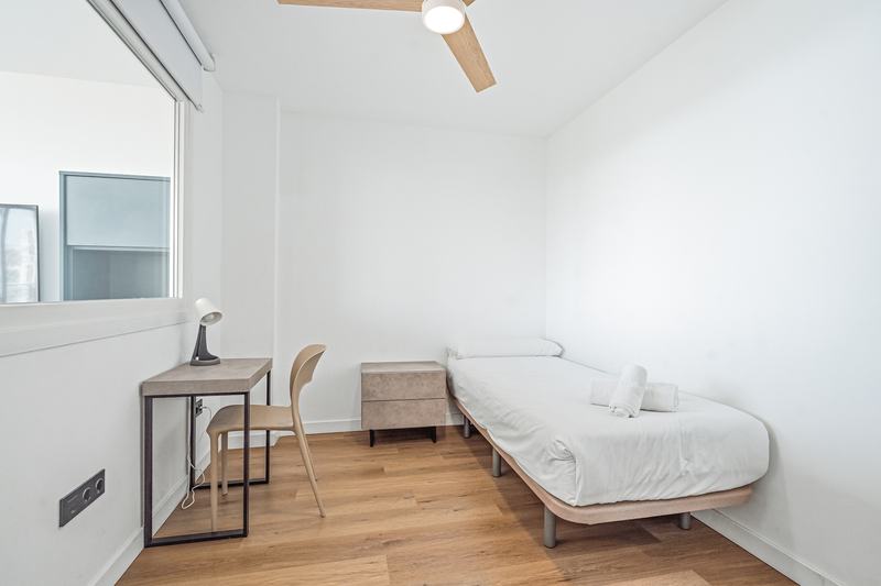 Dormitorio individual con escritorio y ventilador de techo