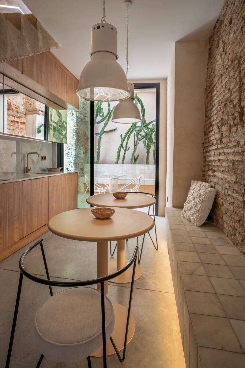 Cocina de madera con lámparas industriales y patio de cactus al fondo