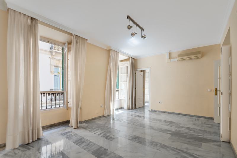 Sala alargada con cortinas y balcón a la calle