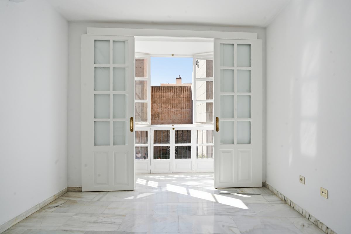 Salón de un piso clásico reformado con puertas de cuarterones abiertas y luz de mediodía