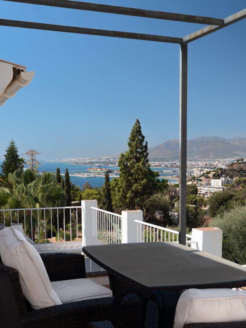 Comedor exterior bajo pérgola con vistas al puerto de Málaga