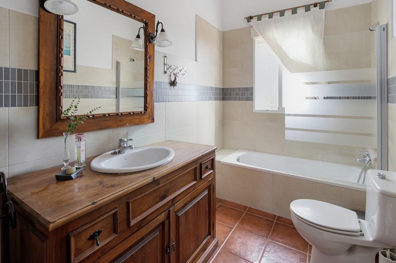 Baño con mueble de madera, espejo tallado y bañera