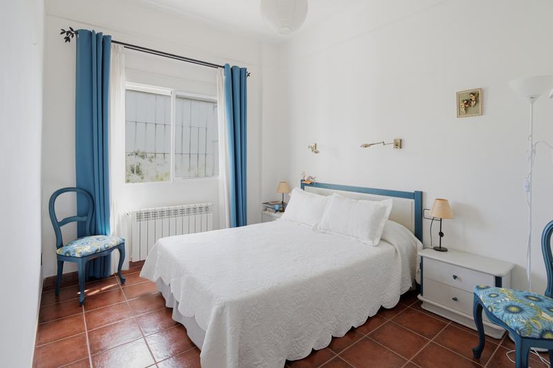 Dormitorio con cortinas azules y cabecero de forja