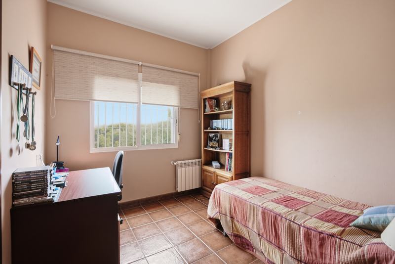 Dormitorio individual con estantería y ventana al campo