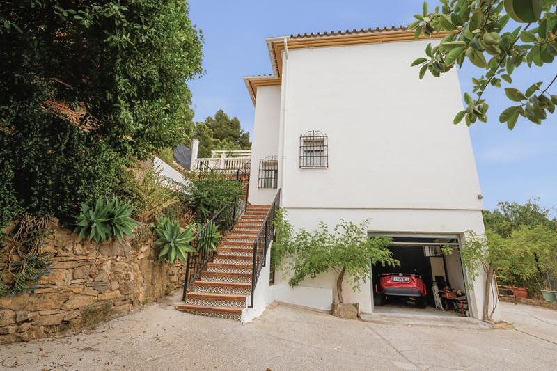 Lateral de la casa con escalera exterior y garaje abierto