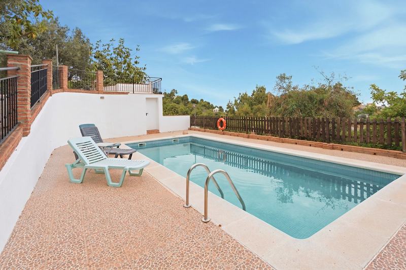 Piscina con cerca de madera y ladera arbolada al fondo