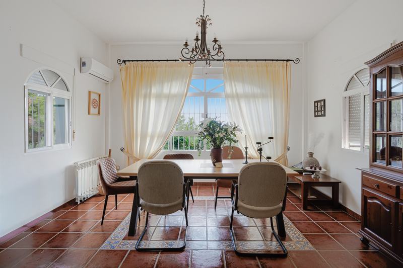 Salón comedor con lámpara de araña y suelo de barro cocido